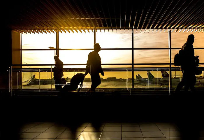 People walking through an airport terminal at sunrise
