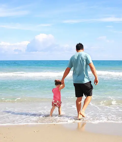 Father and daughter walking along the beach