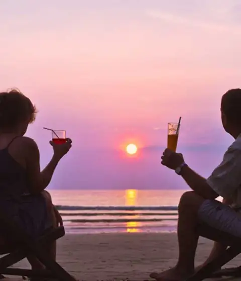 Couple relaxing on the beach at sunset
